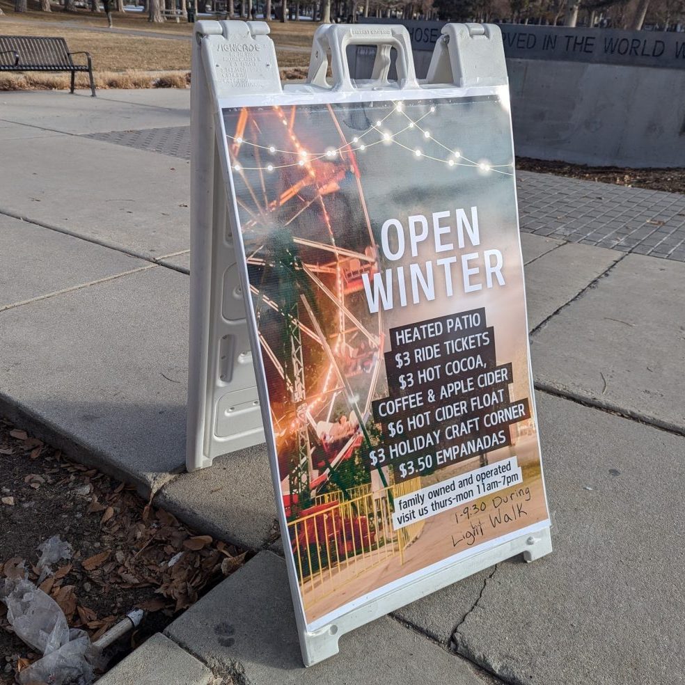photograph of a sandwich board advertising the hours and food menu at the liberty park concession stand